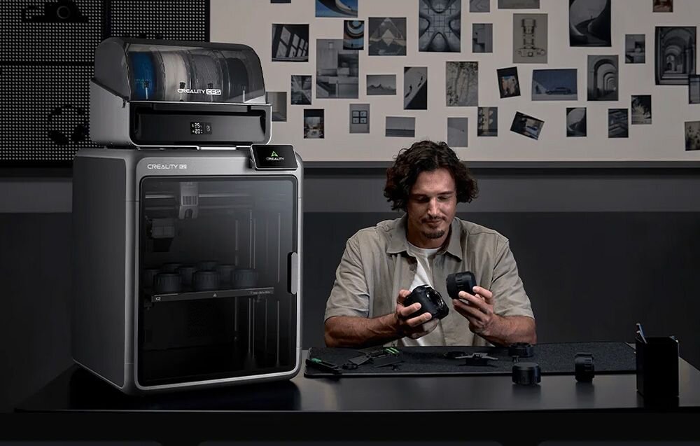 Mężczyzna przy biurku sprawdzający element wydrukowany na drukarce 3D Creality K2 Plus Combo prędkość druku przyspieszenie zaawansowany układ serwomechaniczny sztywna konstrukcja obudowy