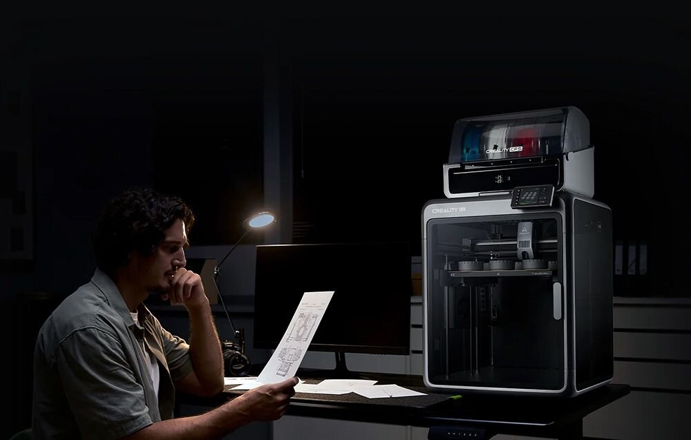 Projektant analizujący dokumentację techniczną przy oświetlonym biurku obok drukarki 3D w nocy automatyczne poziomowanie stołu skraca czas przygotowania system monitoruje proces wykrywa błędy