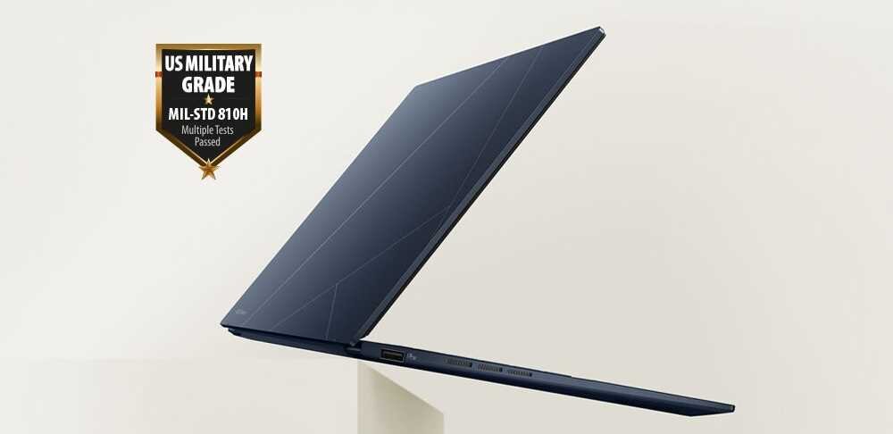 Laptop ASUS Zenbook 14 w kolorze granatowym, lekko otwarty, z widocznym logo certyfikatu wytrzymałości MIL-STD-810H na jasnym tle.  