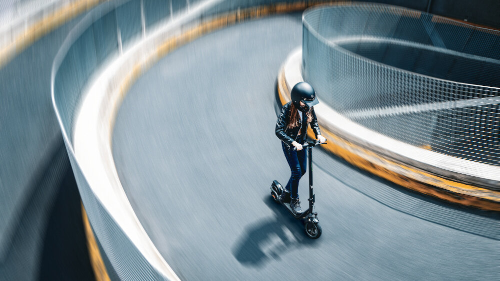 Hulajnoga elektryczna ACER PREDATOR Series ES Storm 60km 500W Amortyzacja 10 cali Czarny osoba opiera się o kierownicę hulajnogi w pokoju silnik moc 500 W prędkość do 20 km/h 4 tryby jazdy dostosowanie jazdy do swoich potrzeb