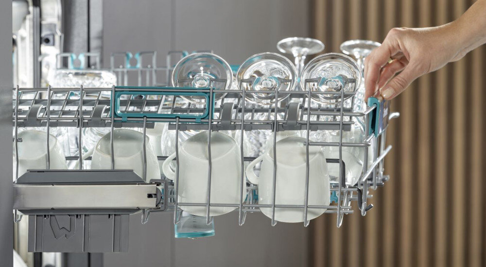 Zmywarka HISENSE HV673B66 zdjęcie lifestyle dłoń pełen kosz naczynia miski kubki wysuwanie łatwe przesuwanie górnego kosza prowadnice kółkowe ciche płynne Przesuwanie komfort obsługi