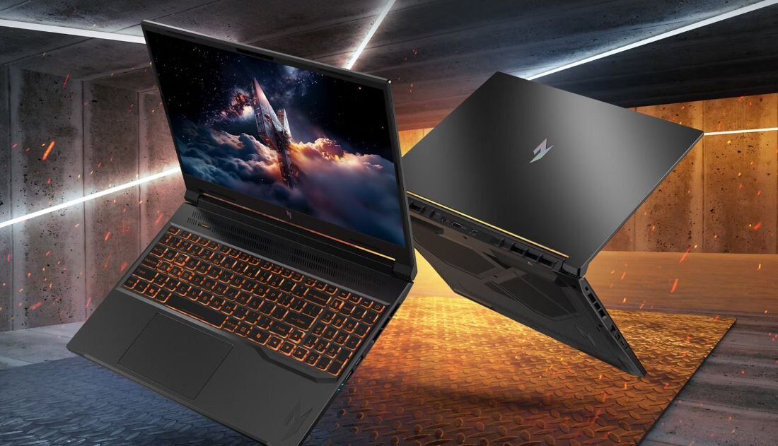 Dwa laptopy z podświetlaną klawiaturą i ekranem wyświetlającym dynamiczną grafikę kosmiczną, umieszczone w industrialnym otoczeniu. Na obudowie widoczne jest logo producenta.