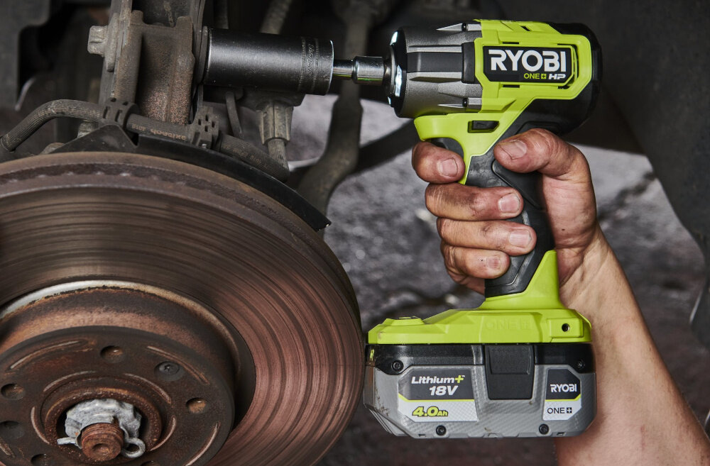 Akumulator RYOBI RC18120A-140X 4Ah 18V + ładowarka warsztat osoba przykręca śruby do podwozia samochodowego w dłoni trzyma wiertarko-wkrętarkę akumulator umieszczony w narzędziu akumulator ma pojemność 4,0 Ah i napięcie 18 V kompatybilność ze wszystkimi narzędziami z serii RYOBI 18 V ONE+ elastyczne wykorzystanie tego samego akumulatora w różnych urządzeniach