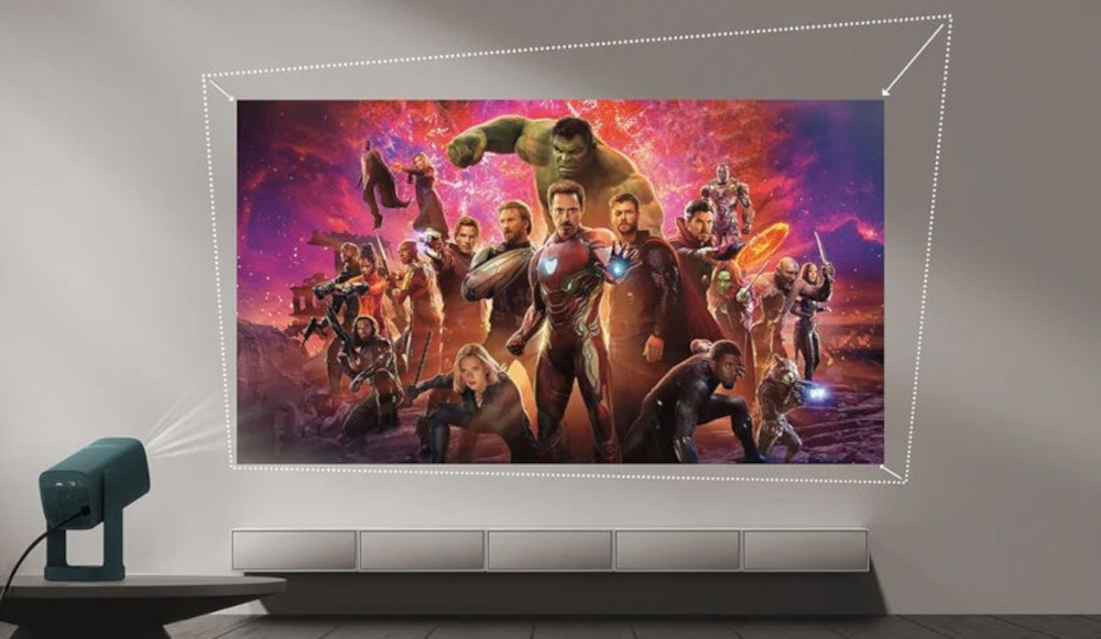 Na ścianie wyświetlany jest obraz z postaciami w kostiumach superbohaterów na tle kolorowego nieba. Obok znajduje się projektor skierowany na ścianę.