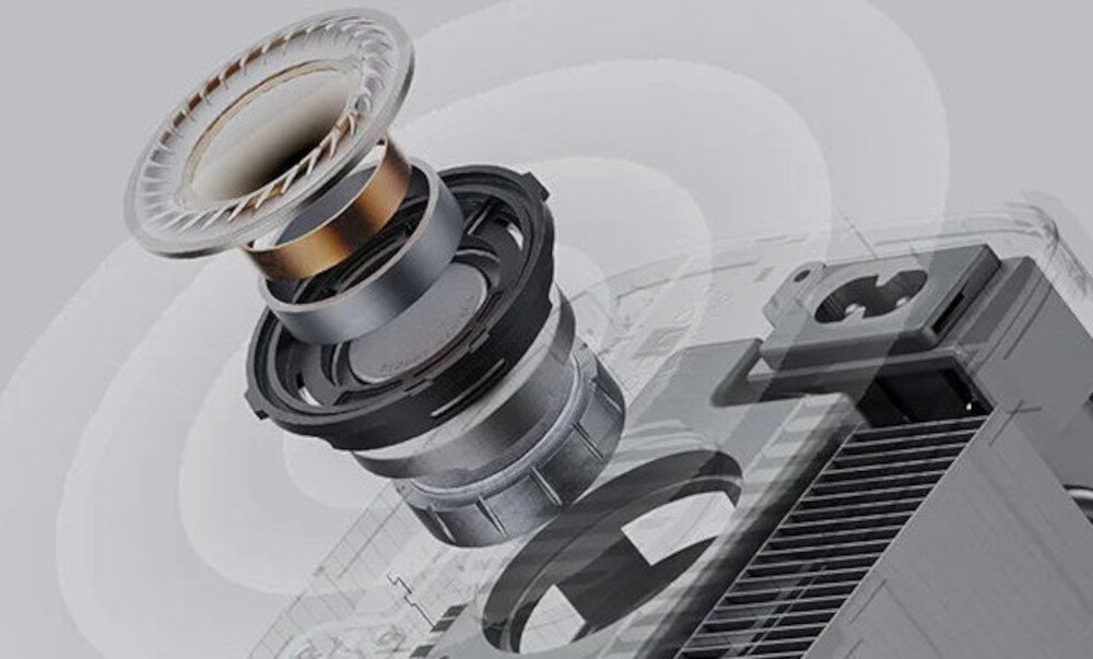 Obraz przedstawia zbliżenie na elementy optyczne projektora, ukazujące soczewki i mechanizmy wewnętrzne. W tle widoczna jest część obudowy projektora z kratką wentylacyjną.