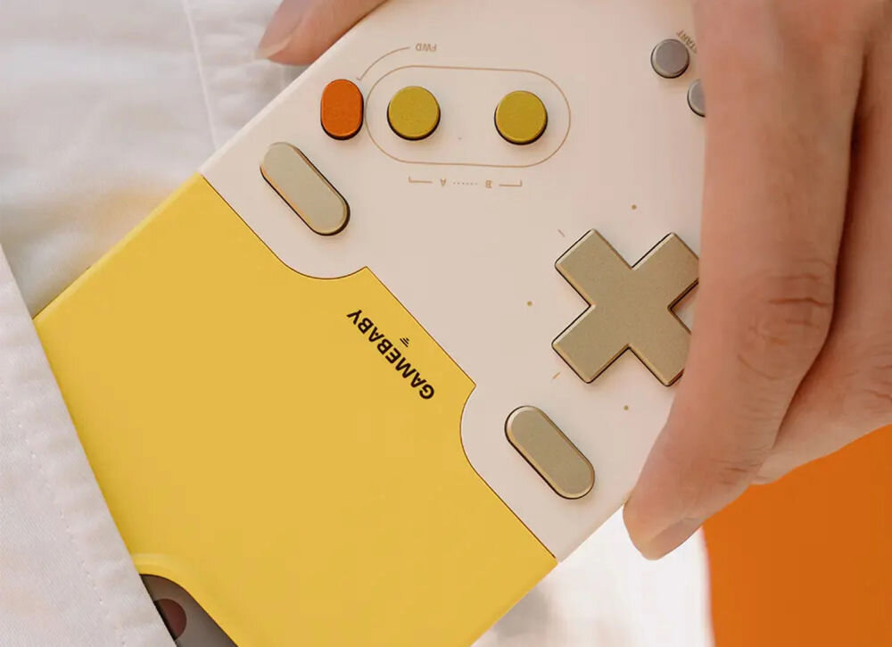 GameBaby retro gry na iPhone Dwuczęściowe etui GameBaby w kolorze szarym i żółtym. Widoczny dolny moduł z fizycznym krzyżakiem, przyciskami AB oraz przyciskami funkcyjnymi, gotowy do nałożenia na dół smartfona.