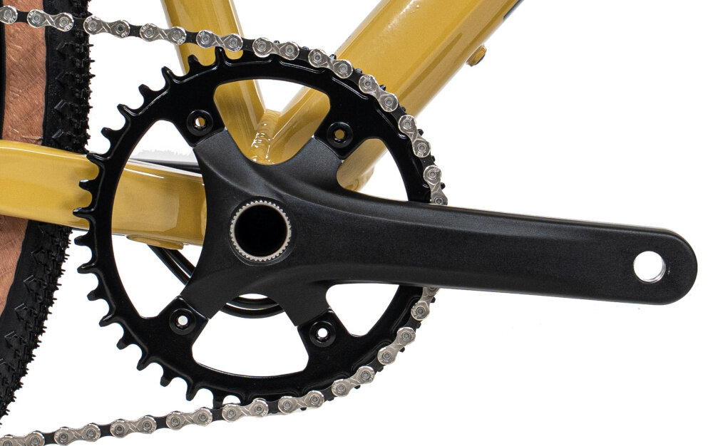 Rower gravel ROMET Aspre 2.1 2854M110-A U21 28 cali Ciemnożółty zbliżenie na korbę i kasetę białe tło korba Prowheel RPL-FD16S z pojedynczą tarczą 40T kaseta MicroSHIFT Sword CS-104 o zakresie przełożeń 11–48T wkład suportu ROMET do jazdy po zróżnicowanych trasach dopasowanie kadencji do terenu solidny suport wspiera płynne przenoszenie mocy