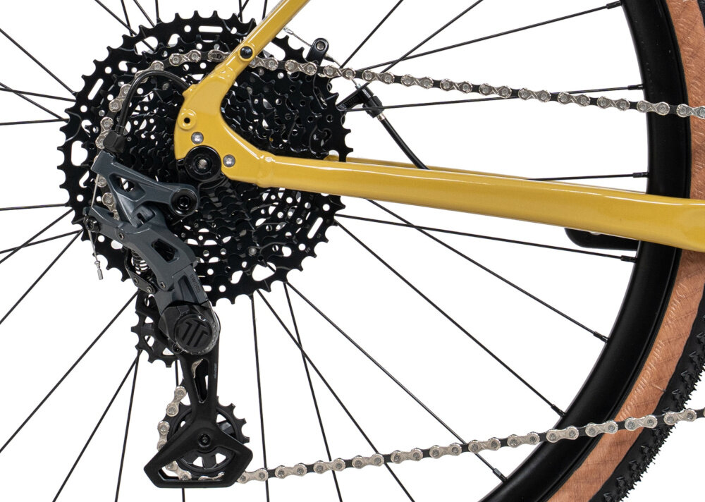 Rower gravel ROMET Aspre 2.1 2856M108-A U22 28 cali Ciemnożółty zbliżenie na tylną przerzutkę przerzutki MicroSHIFT 10 przełożeń duża wytrzymałość sprawne działanie zmiana biegów jest płynna i bezproblemowa tylne przerzutki MicroSHIFT typu Sword G-7005M stabilna praca napędu wszechstronność