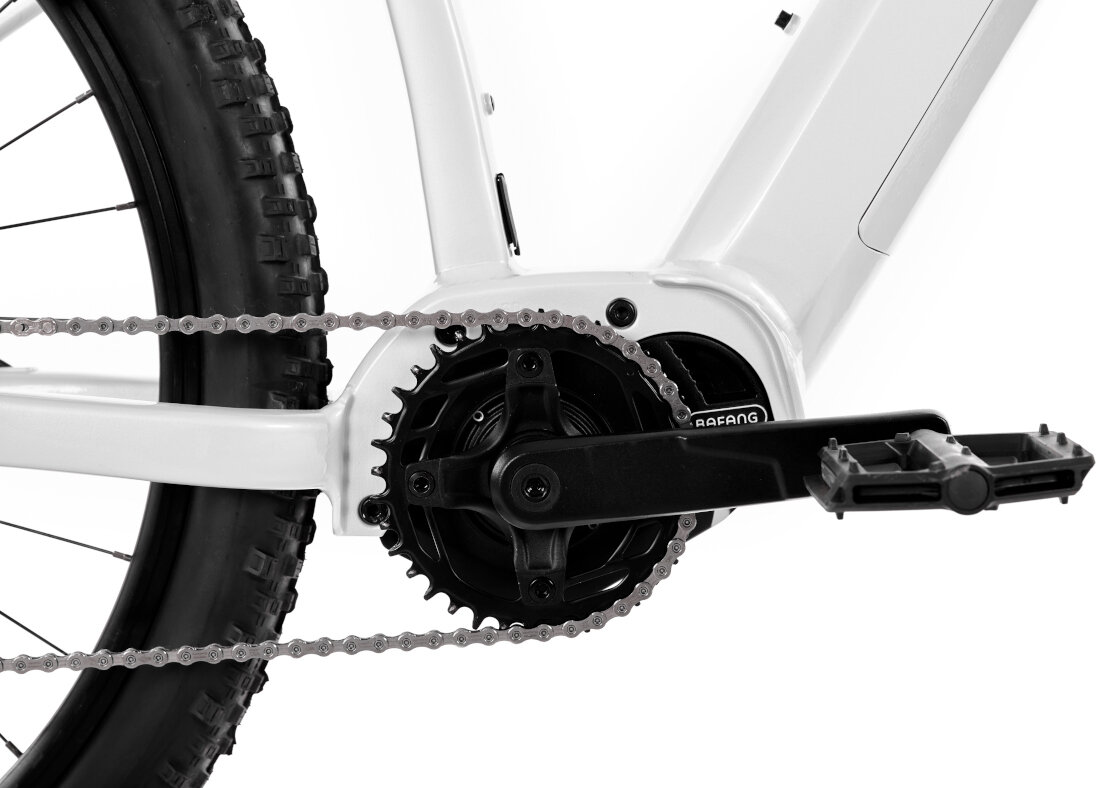 Rower elektryczny ROMET E-Mustang 1.0 U18 29 cali Srebrny Zbliżenie na mechanizm korbowy roweru z widocznym łańcuchem i pedałem. Na ramieniu korby widoczny jest napis \'Prowheel\'.