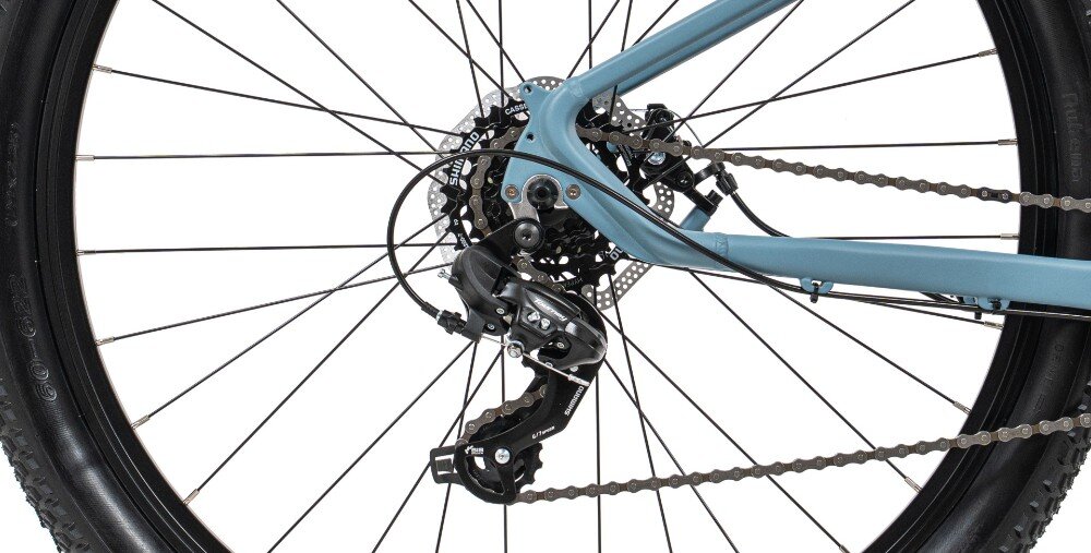 Zbliżenie na tylną część roweru górskiego z widocznym mechanizmem przerzutki i łańcuchem. Rama roweru jest w kolorze niebieskim.