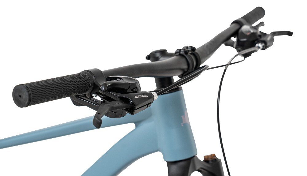 Zbliżenie na kierownicę roweru górskiego z widocznym napisem \'SHIMANO\' na manetce. Rama roweru jest w kolorze niebieskim.