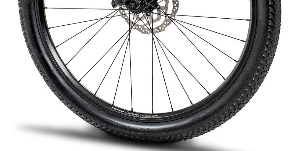 Zbliżenie na koło rowerowe z widocznym bieżnikiem opony i tarczą hamulcową. Opona ma napis \'27.5 x 2.1\'.
