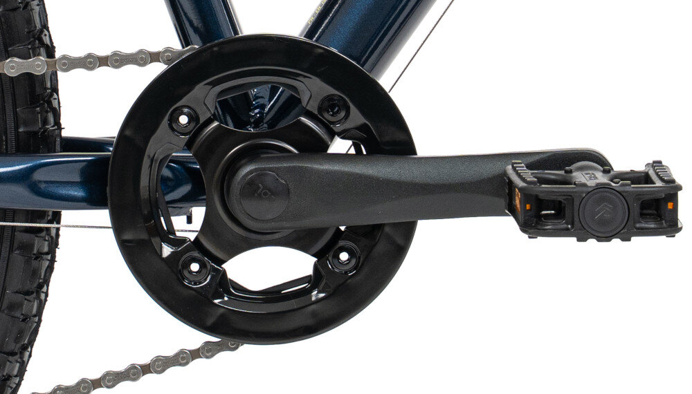 Zbliżenie na mechanizm korbowy roweru z czarną korbą i pedałem. W tle widoczna jest część łańcucha i rama roweru w ciemnym kolorze.