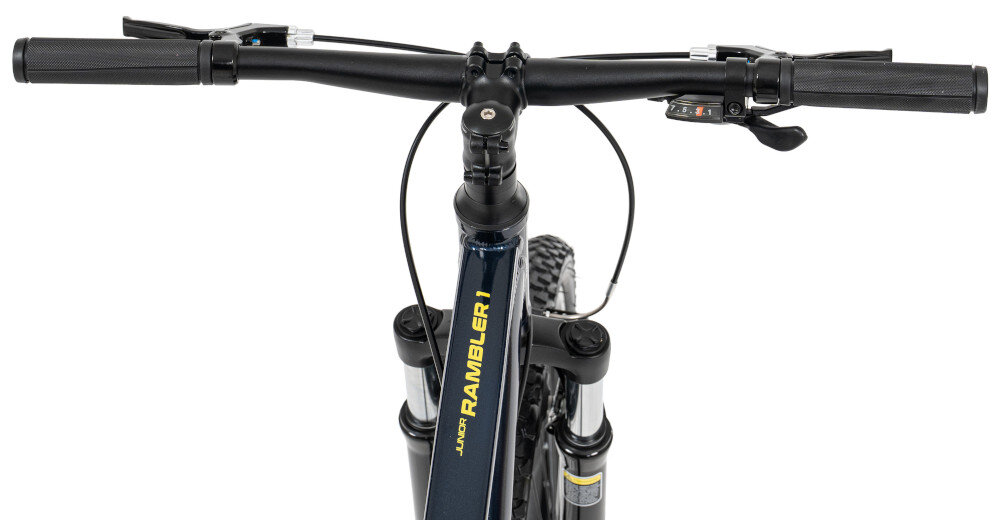 Zdjęcie przedstawia kierownicę roweru z widocznym napisem \'JUNIOR RAMBLER 1\' na ramie. Rower ma czarne uchwyty i elementy mechanizmu zmiany biegów.