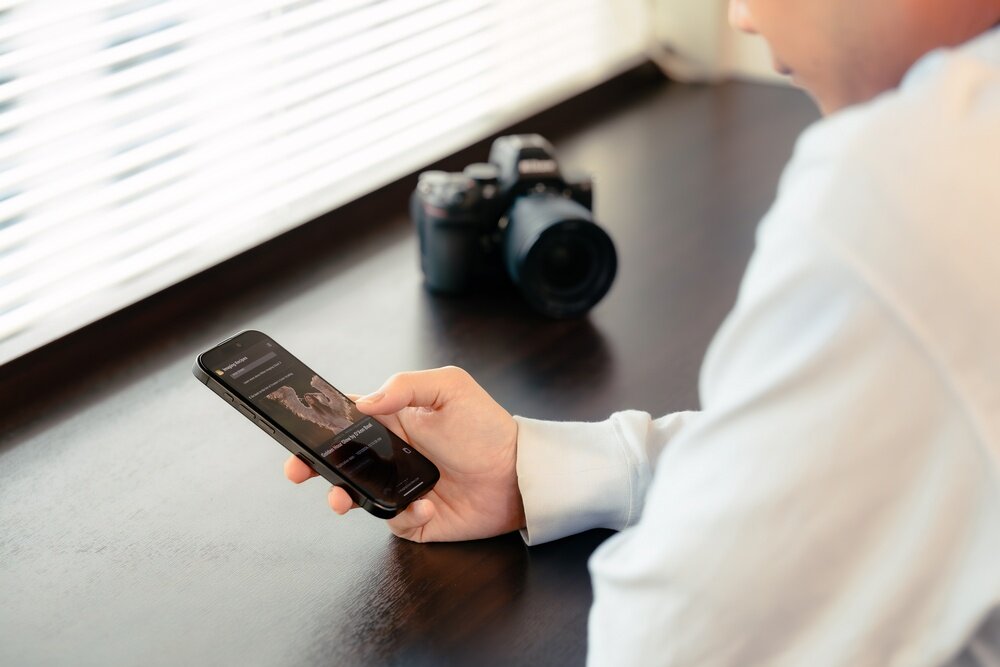 Aparat bezlusterkowy NIKON Z5II człowiek korzysta ze smartfona   