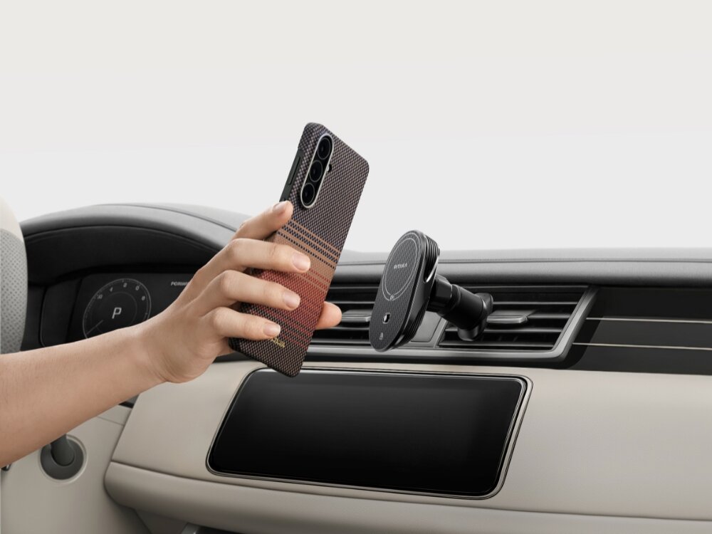 Etui PITAKA Ultra-Slim MagSafe Samsung Galaxy S26 - wytrzymałe włókno, nowoczesny splot Ręka przykładająca smartfon w etui Pitaka Sunset do magnetycznego uchwytu samochodowego zamontowanego na kratce nawiewu.