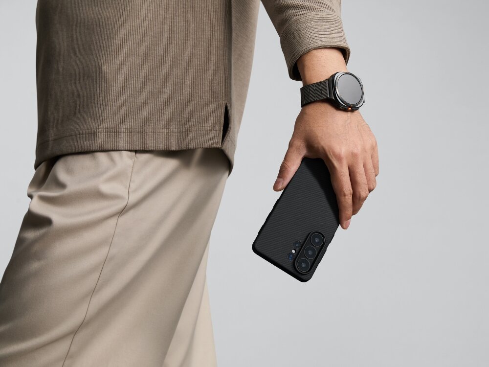 Etui PITAKA MagSafe Samsung Galaxy S26 - włókno aramidowe, smukłe, MagSafe Smartfon Mężczyzna trzymający smartfon w etui Pitaka o wzorze aramidowym, prezentujący dopasowany pasek do zegarka typu smartwatch.