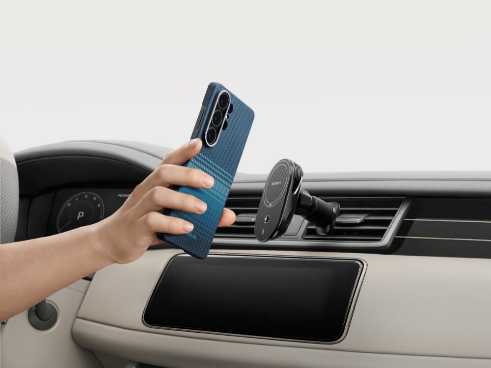 Etui PITAKA MagSafe Samsung Galaxy S26 - wytrzymałe włókno, nowoczesny splot Ręka przykładająca smartfon w etui Pitaka do magnetycznego uchwytu samochodowego zamontowanego na kratce nawiewu.