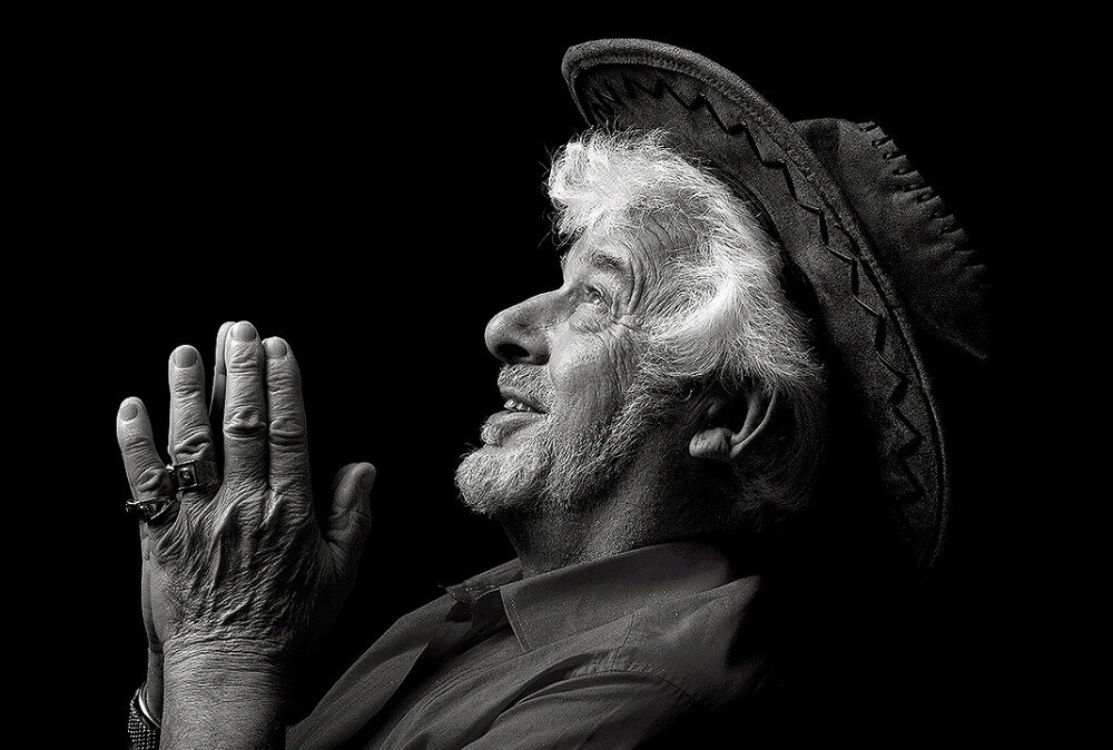 Monitor LG UltraFine 27U730A-B czarno-białe zdjęcie profilowe starszego mężczyzny w kapeluszu ze złożonymi dłońmi na ciemnym tle, prezentujące wysoki kontrast i szczegółowość obrazu