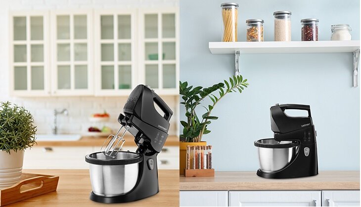 Na obrazie widoczny jest czarny mikser z misą marki ZELMER, umieszczony na blacie kuchennym. W tle znajdują się szafki kuchenne oraz półka z pojemnikami na produkty spożywcze.