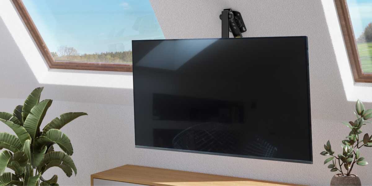 Uchwyt HAMA do TV 19-46 cali 220876 Telewizor zamontowany na czarnym uchwycie sufitowym w salonie na poddaszu z oknami dachowymi.
