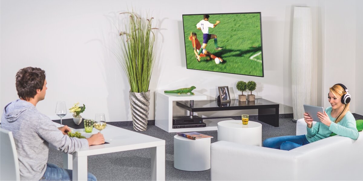 Uchwyt HAMA do TV 19-48 cali 220855 Biało-czarny Telewizor zamontowany na ruchomym uchwycie ściennym, obrócony w stronę osób spędzających czas w salonie i jadalni