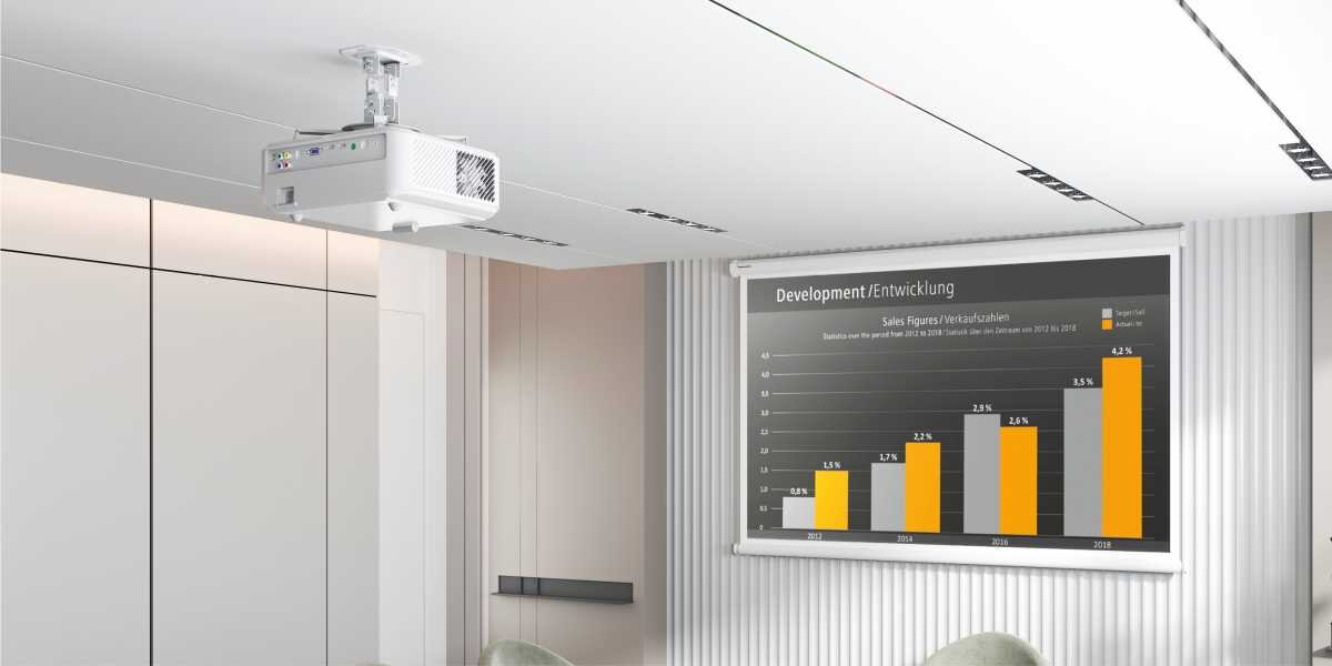 Uchwyt sufitowy HAMA 220879 Maksymalne obciążenie 13.5 kg Projektor na uchwycie sufitowym w nowoczesnej sali konferencyjnej wyświetlający wykresy biznesowe na ekranie projekcyjnym.