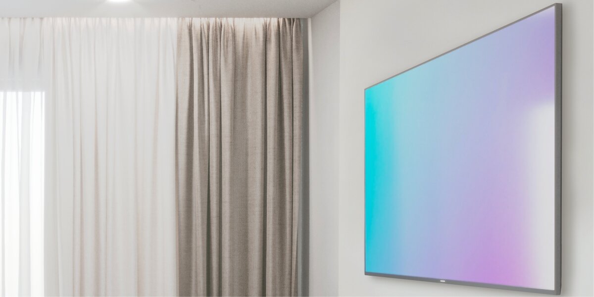 Uchwyt do TV HAMA 37-80 cali, obrót 360 stopni Nowoczesny, płaski telewizor zamontowany blisko ściany w minimalistycznym salonie z jasnymi zasłonami.