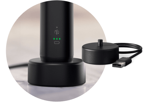 Szczoteczka umieszczona w podstawce ładującej. Obok znajduje się podstawka ładująca.