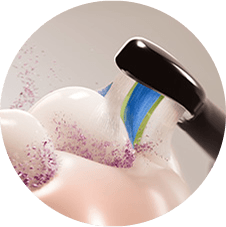 Zbliżenie na szczoteczkę usuwającą z zębów rozbitą płytkę.