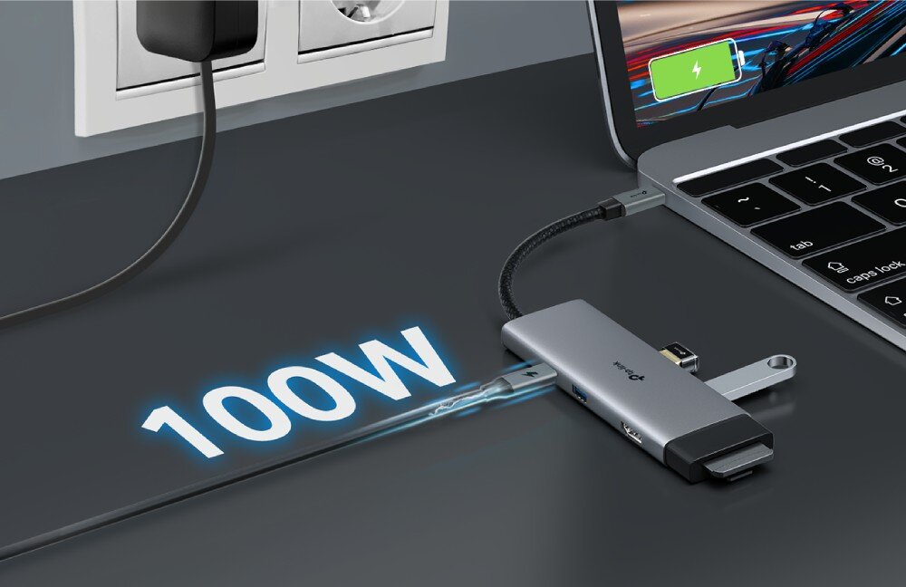 Hub TP-LINK UH7021C Zbliżenie na adapter podłączony do laptopa, do którego wpięty jest kabel zasilający biegnący od gniazdka ściennego, z nałożoną grafiką świetlną '100W' sugerującą szybkie ładowanie