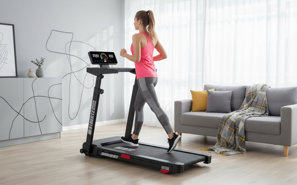 Bieżnia elektryczna HERTZ FITNESS Intro 932W 12km-h pokój osoba biegnie na bieżni wokół meble napisy z wymiarami zdrowie kondycja pasja bieganie chodzenie