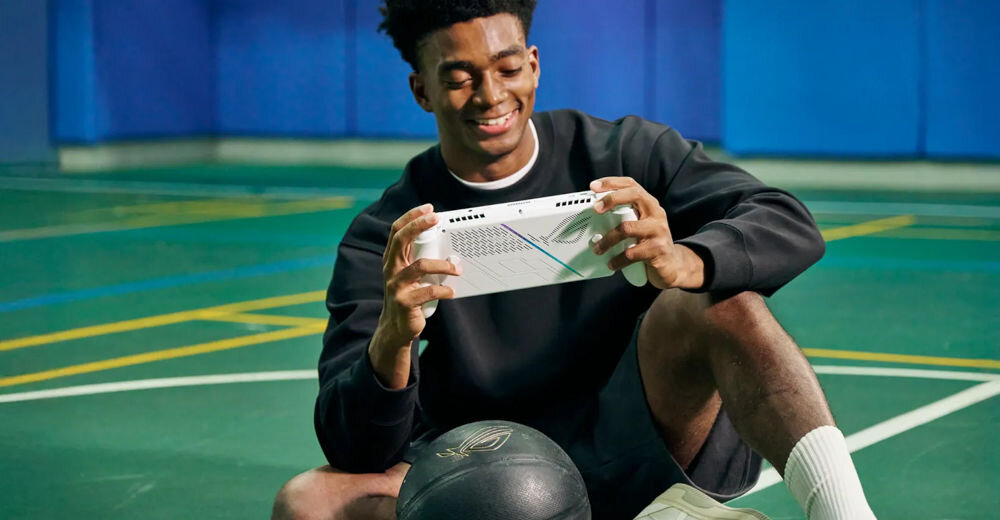 ASUS ROG Xbox Ally RC73YA biały przedstawienie konsoli podczas użytkowania mężczyzna siedzący na boisku z piłką i grający na konsoli system Windows prosty interfejs