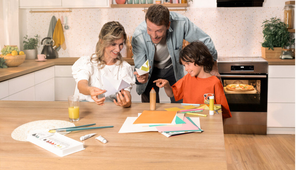 KUCHNIA GORENJE MEKIS6101I lifestyle kuchnia rodzina dziecko akcesoria plastyczne na stole kuchenka w tle kolor czarno srebrny okap półki czajnik akcesoria kuchenne na blacie