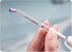 Osoba trzyma przezroczystą końcówkę irygatora z fioletową końcówką. Na końcówce widoczny jest napis \'Philips Sonicare\'.
