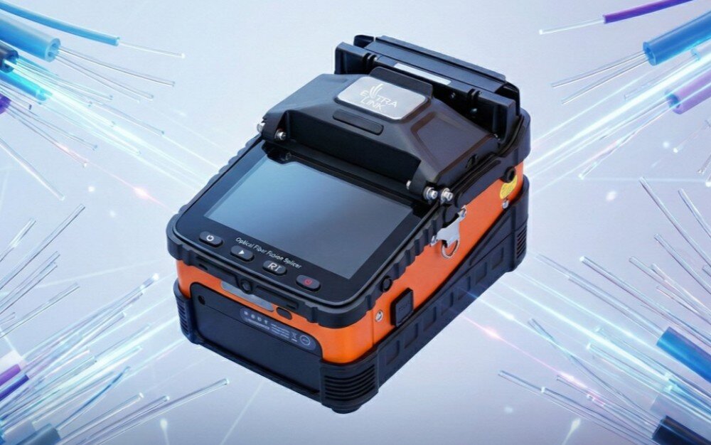 Spawarka światłowodowa EXTRALINK AI-5 Pro Pomarańczowo-czarna spawarka światłowodowa z dużym wyświetlaczem, ujęta pod kątem na jasnym tle w otoczeniu graficznych przedstawień świecących włókien światłowodowych