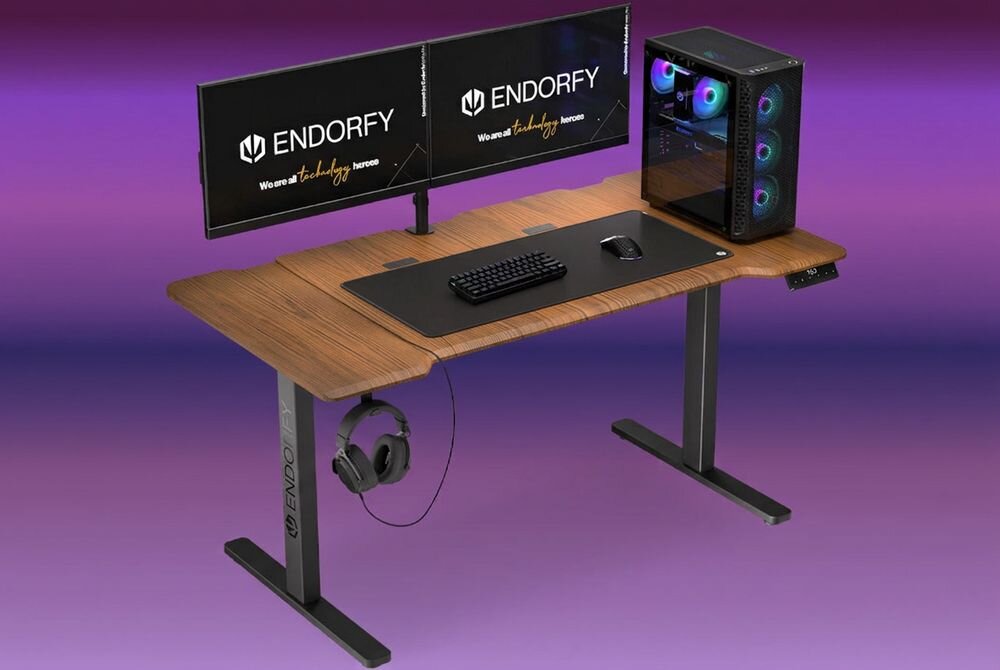 Na obrazie widoczne jest biurko z dwoma monitorami, klawiaturą, myszką i komputerem stacjonarnym. Na monitorach widnieje logo \'ENDORFY\' oraz tekst \'We are all technology heroes\'.