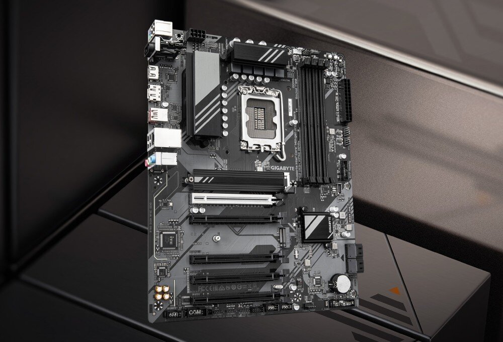 Komputer MAD DOG GeForce RTX5070 DLSS 4 Reflex Edition 2 ENDORFY500AIR-I24DB32 Płyta główna w formacie ATX w ciemnej kolorystyce z widocznym gniazdem procesora, slotami pamięci RAM, złączami PCIe oraz radiatorami umieszczona na tle geometrycznej powierzchni, płyta główna, układ zasilania, radiatory, łączność Wi-Fi