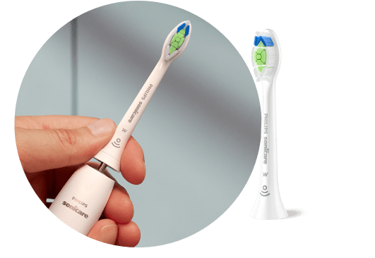 Dłoń trzymająca szczoteczkę z wyjętą końcówką. Obok znajduje się końcówka szczoteczki.