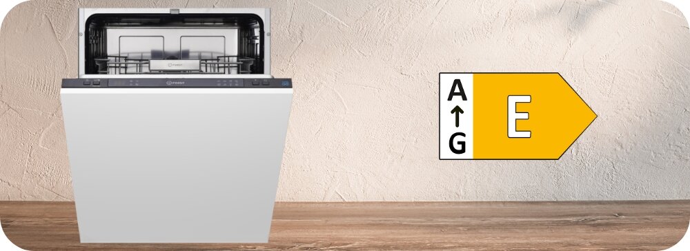 ZMYWARKA INDESIT IN2IE13CNO8 Na obrazie widać zmywarkę o klasie energetycznej E stojącą na drewnianym blacie. Ikona energetyczna po prawej informuje o poziomie zużycia energii oszczędne zużycie energii efektywne mycie naczyń