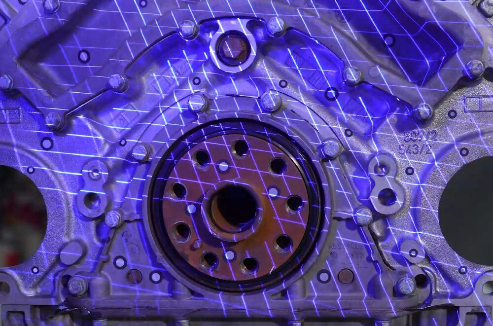 Skaner 3D CREALITY Sermoon S1 Zbliżenie na metalową, odlewaną część silnika, pokrytą siatką wyświetlanych, niebieskich linii laserowych, skanowanie, tryby, rozdzielczość