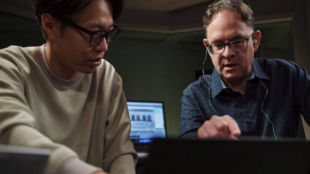 Słuchawki dokanałowe SONY WF-1000XM6 ANC Dwaj mężczyźni pracujący przy laptopie w studio, jeden z nich korzysta ze srebrnych słuchawek bezprzewodowych Sony WF-1000XM6.