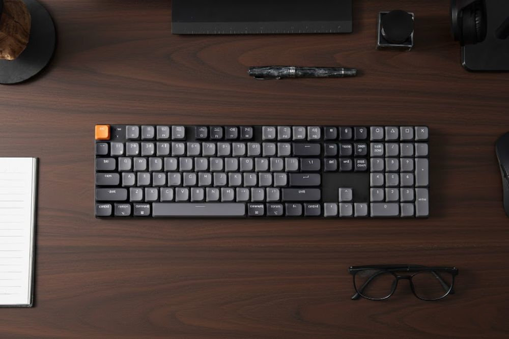 KEYCHRON K5 Technologia Hot-Swap wymianę switchy bez konieczności lutowania Keycapy LSA Shire-through ABS odporne na zużycie i ścieranie - klawiatura na jasnym biurku - klawiatura na ciemnym blacie, obok okulary i marker