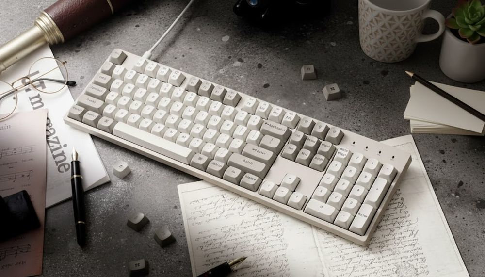 KEYCHRON C2 Pro KEYCHRON C2 Pro 436 × 130 x 28 mm 975 g Lekka konstrukcja stabilna rama - klawiatura na jasnym blacie, obok kubek i okulary 