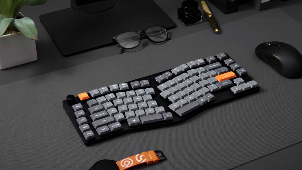 KEYCHRON K15 Max Technologia Hot-Swap wymianę switchy bez konieczności lutowania Keycapy OSA double-shot PBT odporne na zużycie i ścieranie - klawiatura na ciemnym biurku, obok mysz, zegarek i okulary