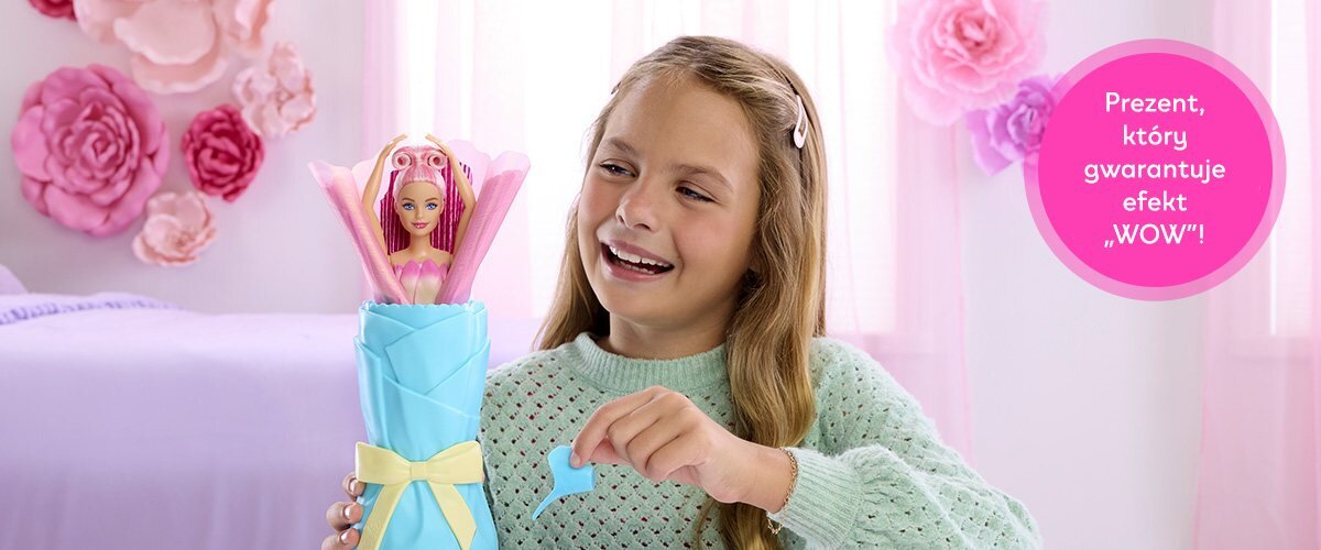 Dziewczynka bawiąca się lalką Barbie w pokoju, obok widnieje napis 'Prezent, który gwarantuje efekt WOW'.