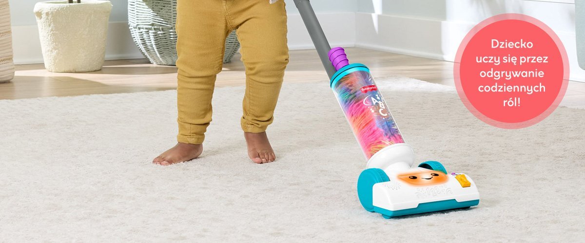 Dziecko bawiące się zabawkowym odkurzaczem Fisher Price, obok widnieje napis 'Dziecko uczy się przez odgrywanie codziennych ról!'.