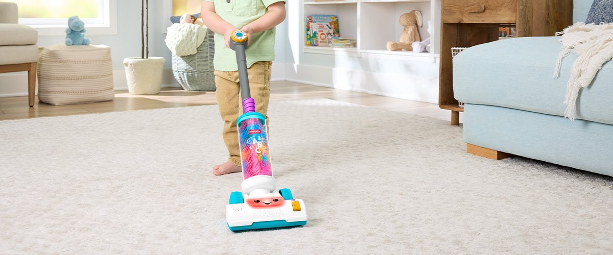 Dziecko bawiące się zabawkowym odkurzaczem Fisher Price.