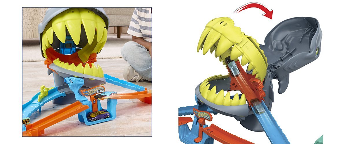 Zabawka przedstawia tor wyścigowy z dużą paszczą rekina, w której znajdują się kolorowe tory. Na torze widoczne jest logo \'Hot Wheels\'.