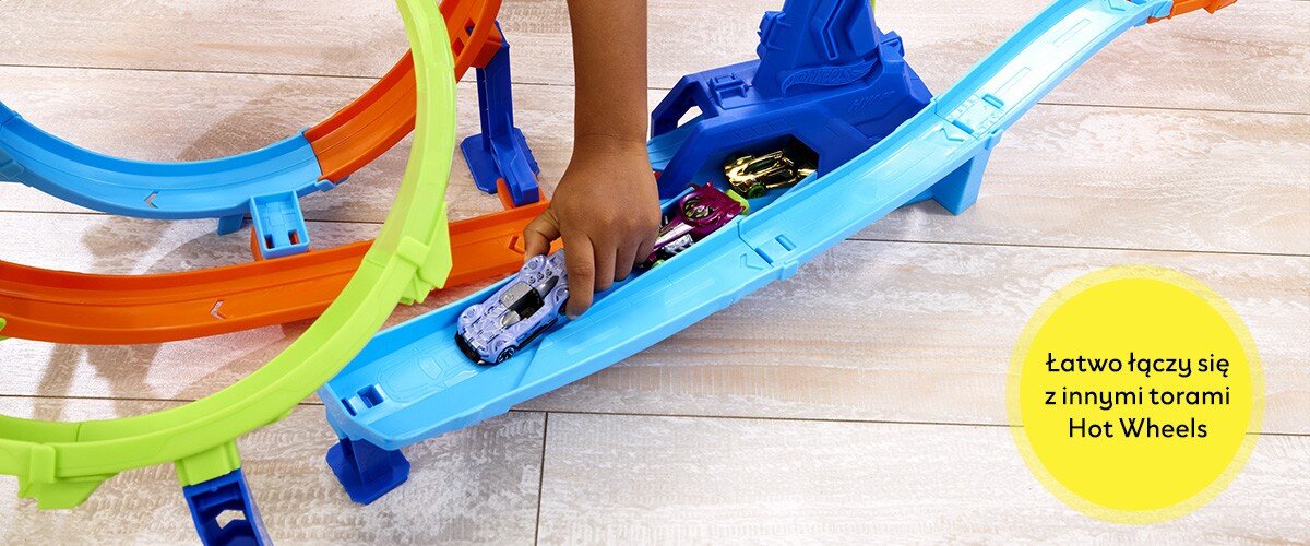 Kolorowy tor wyścigowy z samochodzikami Hot Wheels, na którym widoczna jest ręka dziecka. Na żółtym tle napis: \'Łatwo łączy się z innymi torami Hot Wheels\'.